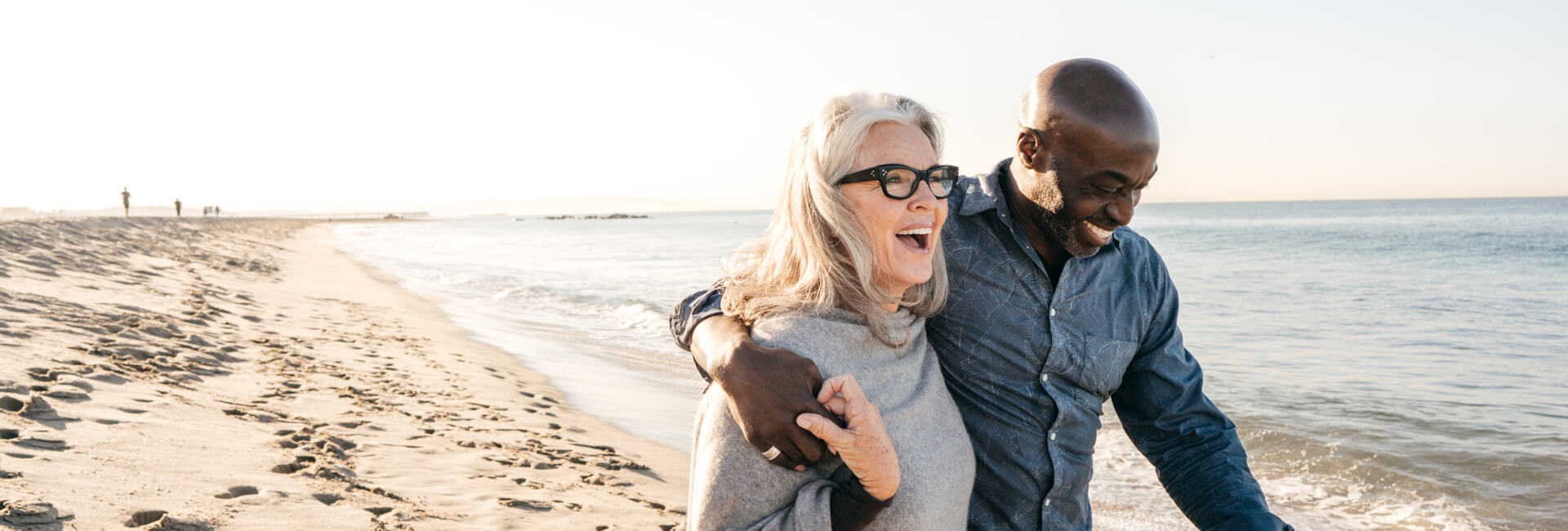 man and woman laughing and walking on the beach