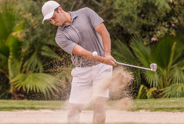Man in sand pit, golfing