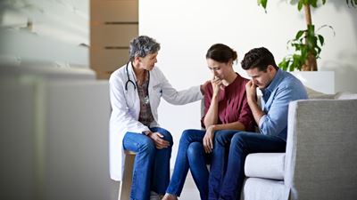 Doctor consoles sad couple