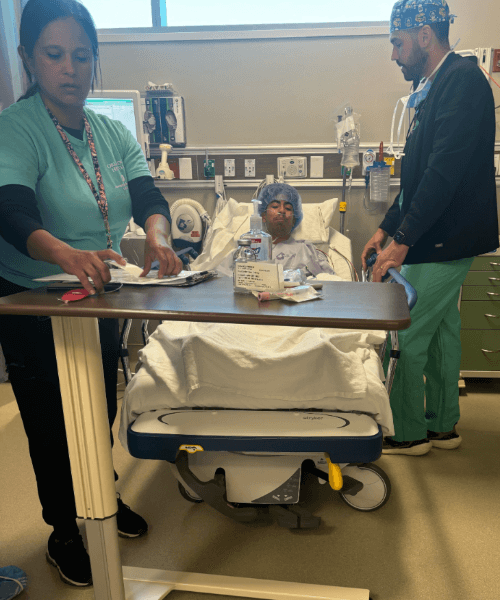 Boy in hospital bed next to 2 doctors
