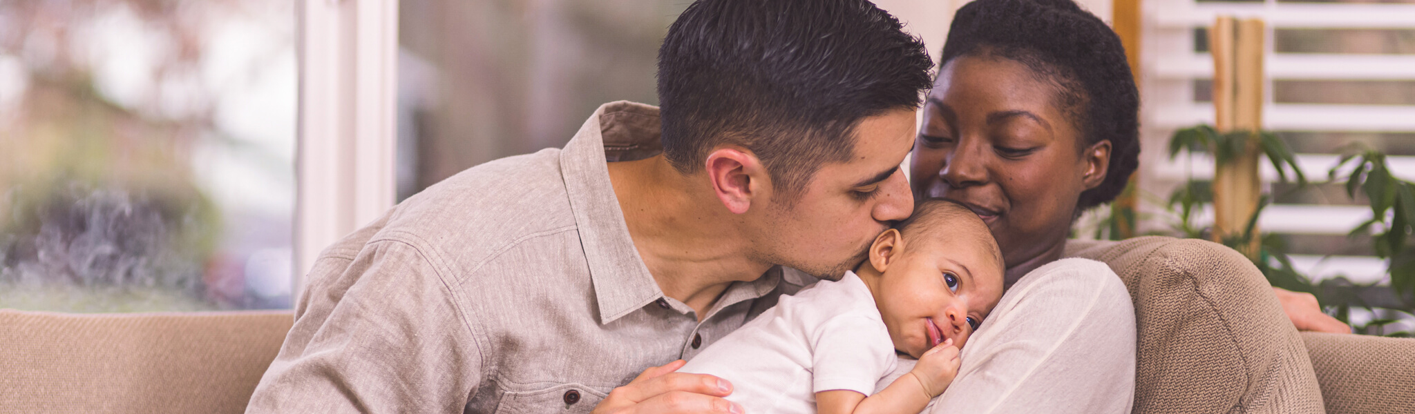 man kissing baby being held by woman