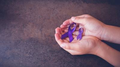 A young girl holding two ovarian cancer awareness ribbons.