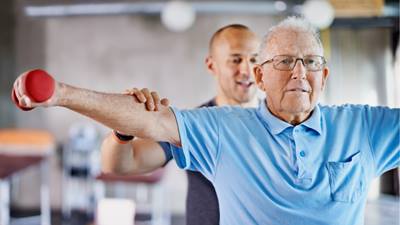 Elderly man working out with a personal trainer.