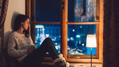 Girl sitting on window sill looking out window