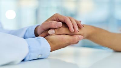 Hospital chaplain holding patients hand