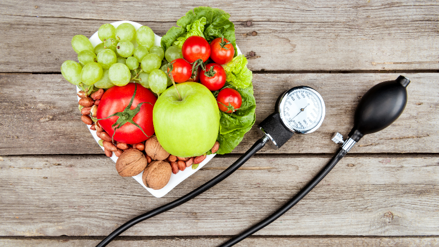 Heart shaped plate with fruits and a blood pressure monitor.